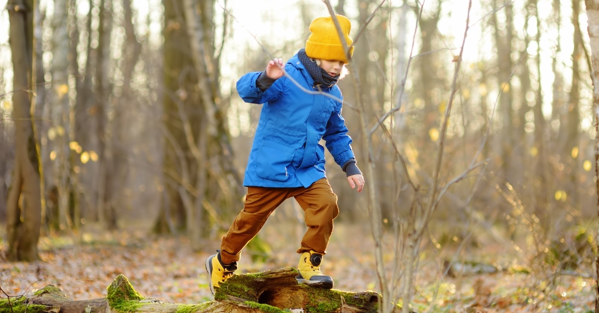 Preschoolers safely jumping onto a low log 